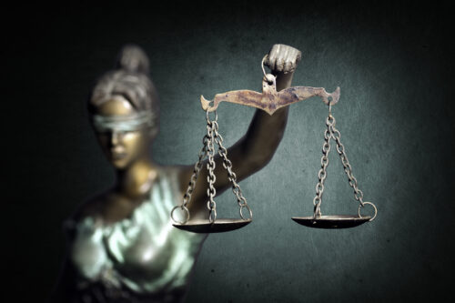 A statue of Lady Justice holding unbalanced scales, symbolizing fairness and legal rights in employment law. The concept of California at-will employment allows employers to terminate workers without cause, but certain legal protections still apply to employees.