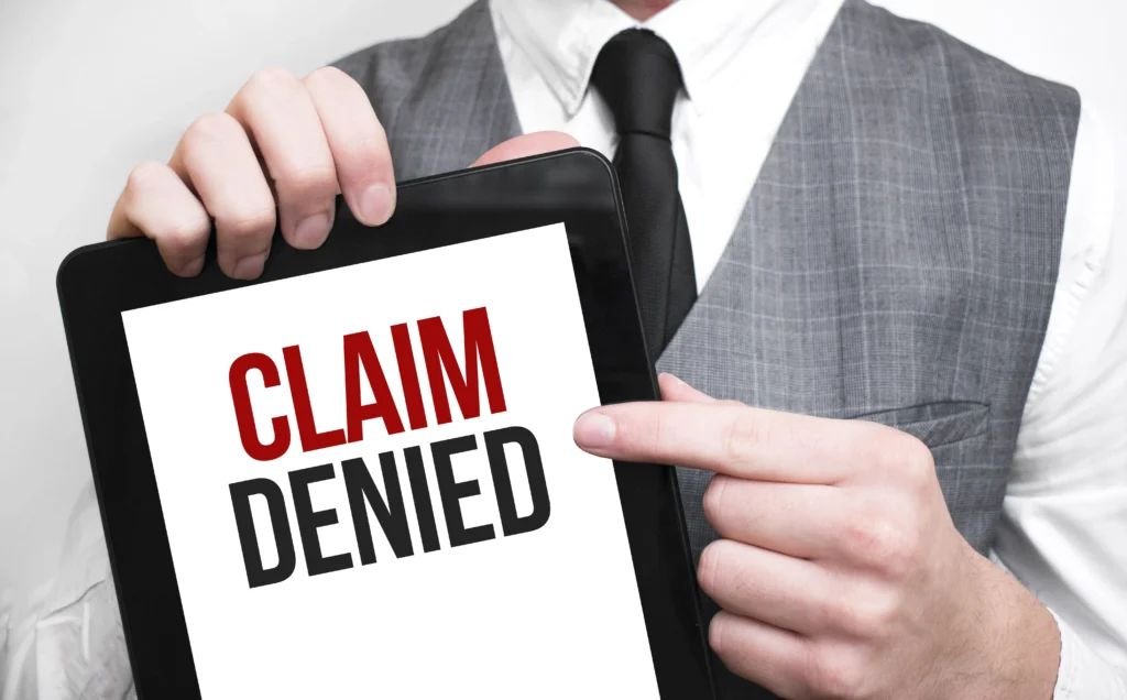Close-up of a person holding a tablet displaying the message 'Claim Denied,' representing challenges homeowners face when a property damage claim has been denied after the Los Angeles fires.