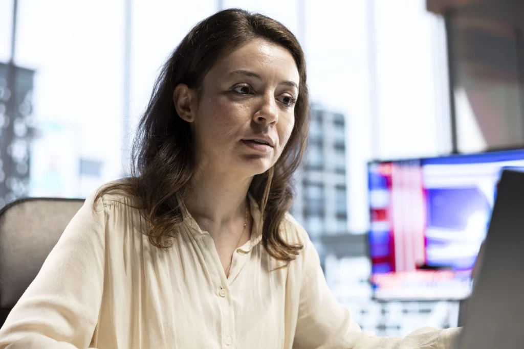 A woman sitting at a desk with a laptop, focused on California's new data breach notification law for employees.