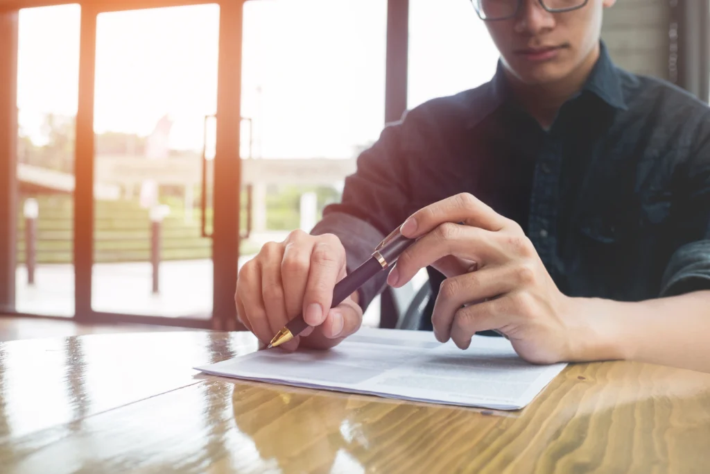 A man prepares to sign a document related to severance agreements in California.