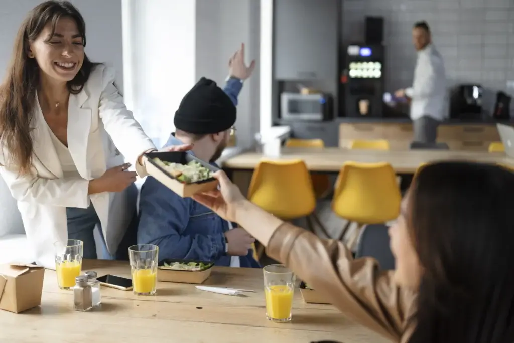 Employees sharing lunch during a workplace break, representing meal and rest break premiums in California.